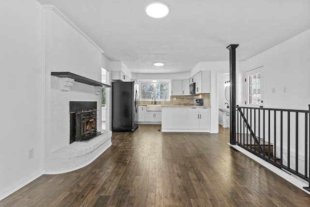 unfurnished living room featuring plenty of natural light, dark wood-type flooring, and sink