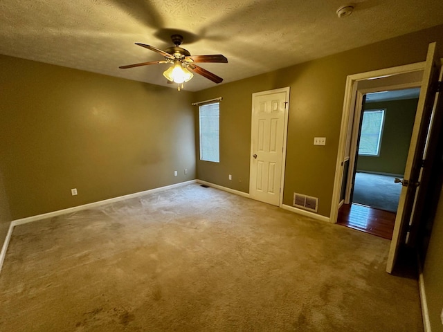 unfurnished bedroom featuring ceiling fan, multiple windows, and a textured ceiling