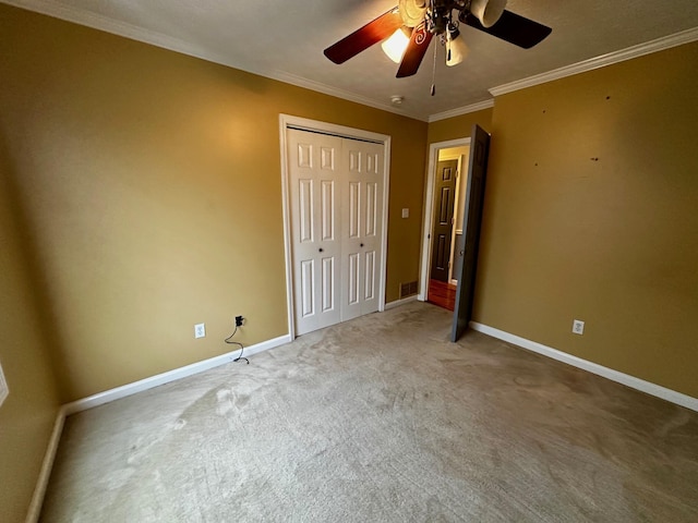 unfurnished bedroom featuring ornamental molding, a closet, ceiling fan, and carpet