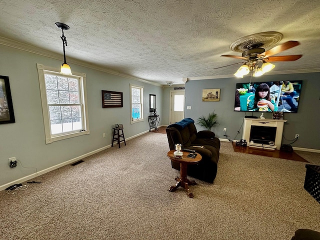 carpeted living room featuring ornamental molding, ceiling fan, a textured ceiling, and a fireplace