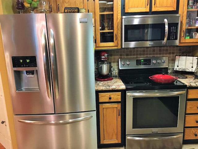 kitchen with light stone countertops, decorative backsplash, and stainless steel appliances