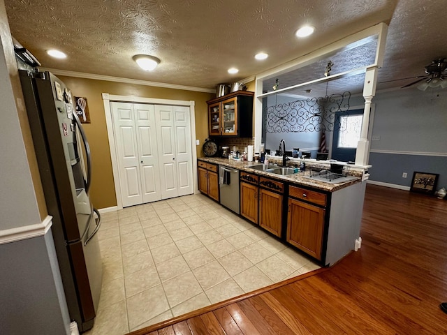 kitchen with sink, ornamental molding, stainless steel appliances, a textured ceiling, and light hardwood / wood-style flooring