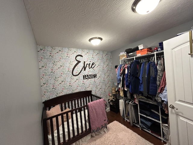 bedroom featuring a crib, a closet, and a textured ceiling