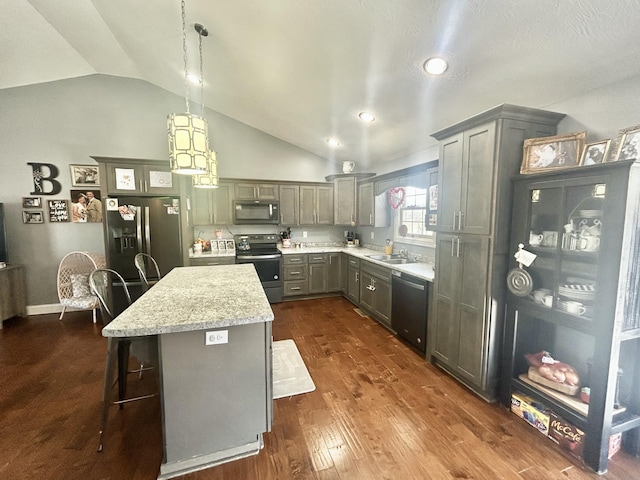 kitchen with lofted ceiling, a breakfast bar, stainless steel appliances, a kitchen island, and decorative light fixtures