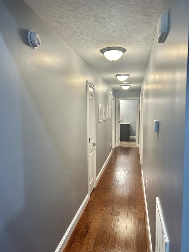 corridor featuring dark hardwood / wood-style floors and a textured ceiling