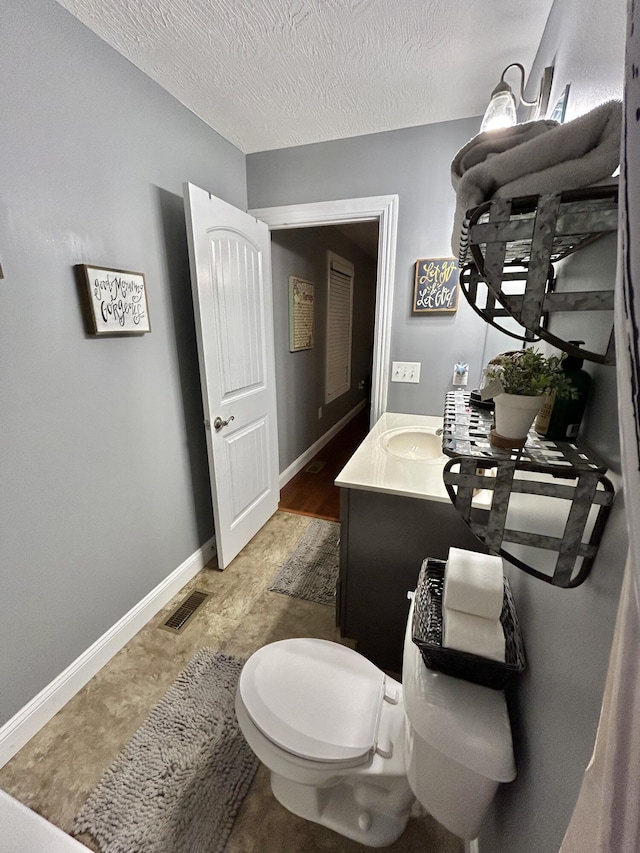 bathroom featuring vanity, a textured ceiling, and toilet