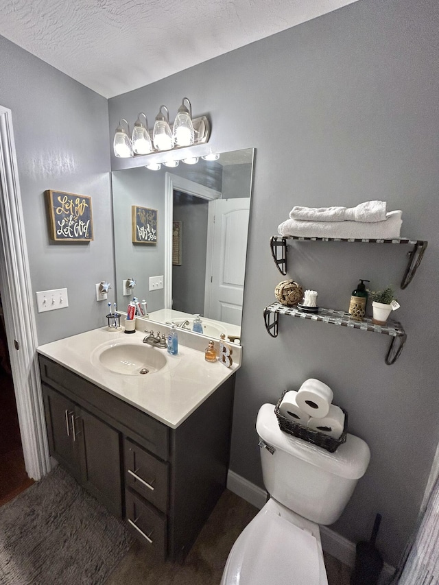 bathroom with vanity, toilet, and a textured ceiling