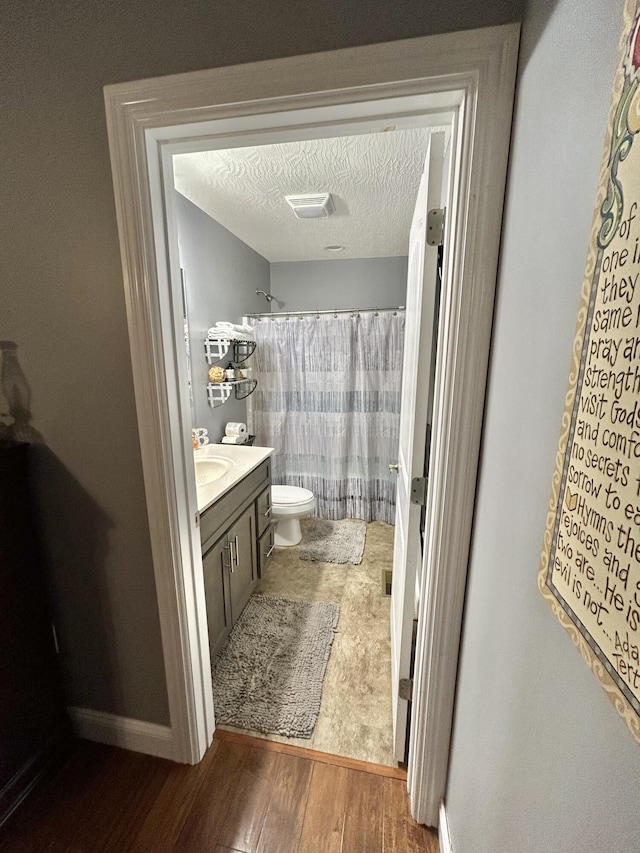 bathroom with vanity, toilet, hardwood / wood-style floors, and a textured ceiling