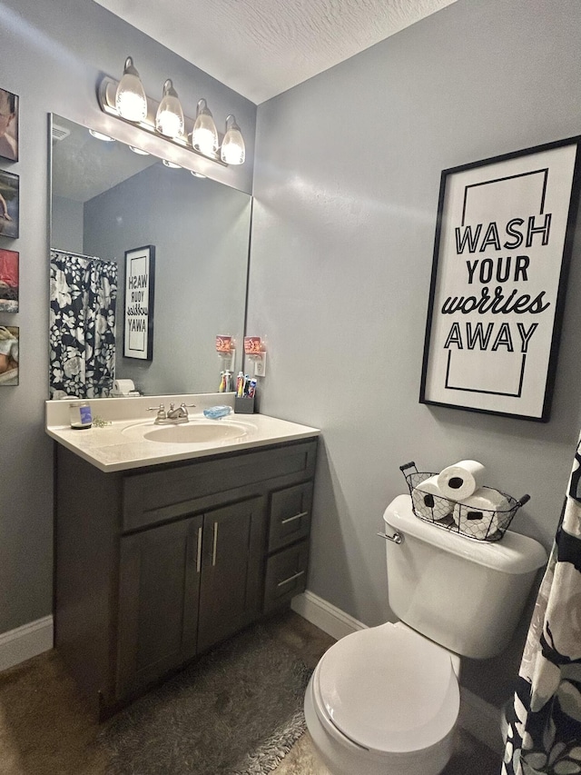 bathroom with vanity, toilet, and a textured ceiling