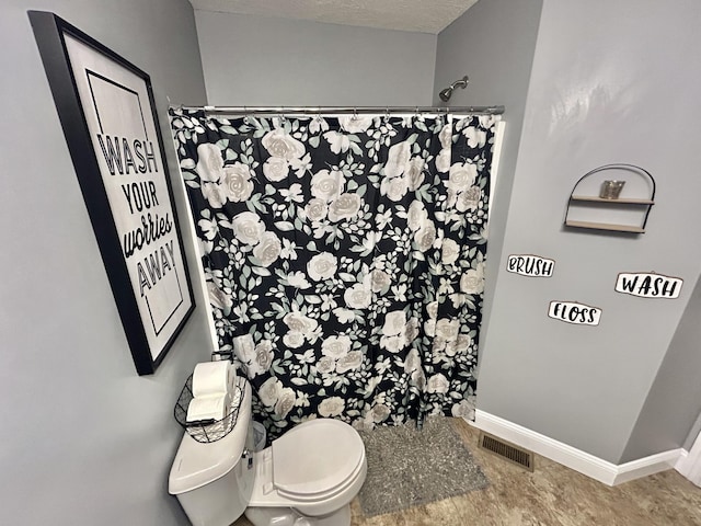 bathroom featuring toilet, a textured ceiling, and a shower with shower curtain