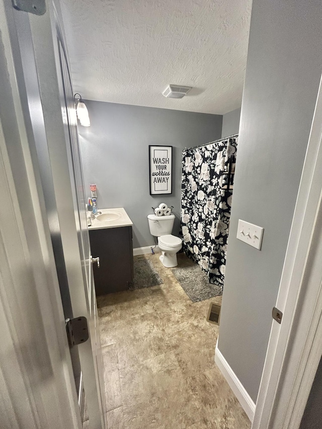 bathroom with vanity, toilet, and a textured ceiling