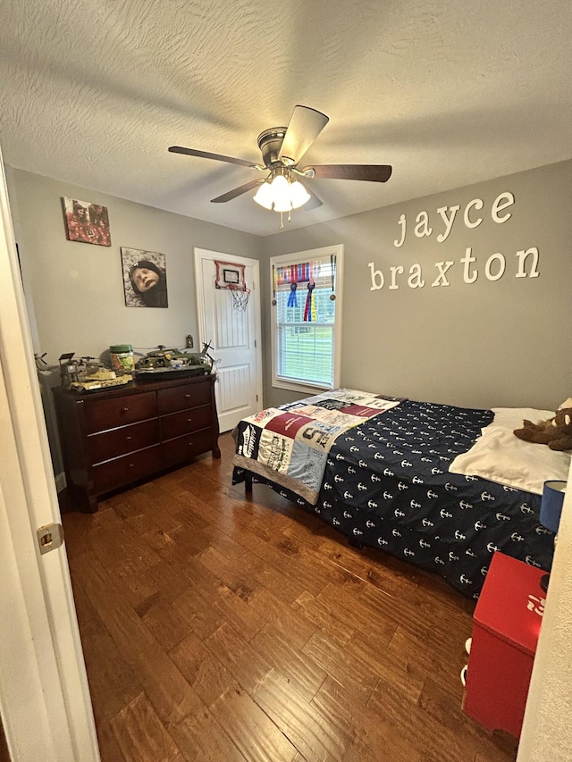 bedroom with ceiling fan, dark hardwood / wood-style flooring, and a textured ceiling