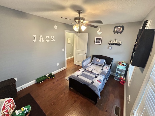 bedroom featuring dark wood-type flooring, a textured ceiling, and ceiling fan