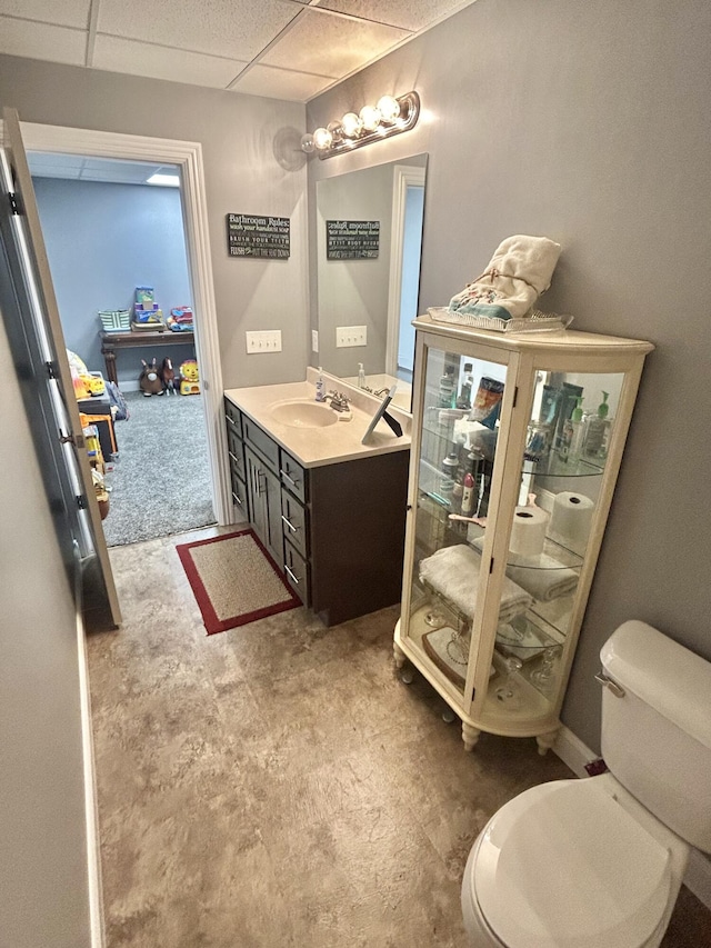 bathroom with vanity, toilet, and a drop ceiling