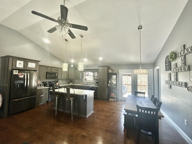 kitchen with pendant lighting, stainless steel appliances, a center island, and vaulted ceiling