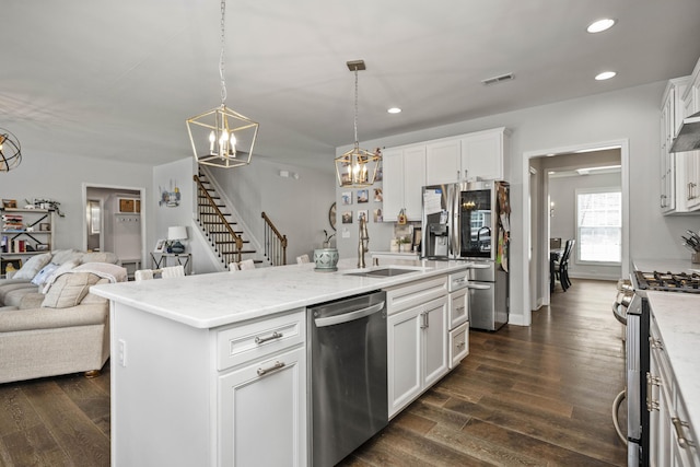 kitchen with dark wood-type flooring, an island with sink, pendant lighting, stainless steel appliances, and white cabinets