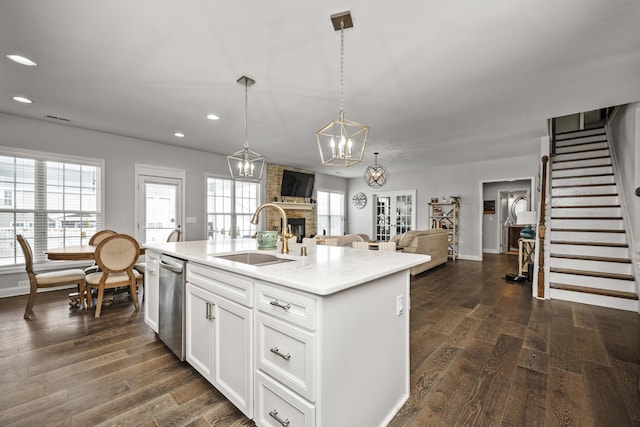 kitchen featuring sink, a center island with sink, stainless steel dishwasher, pendant lighting, and white cabinets