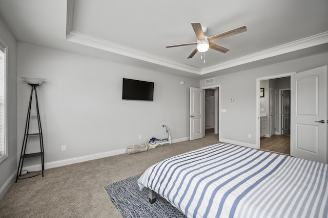 carpeted bedroom featuring ensuite bath, ornamental molding, a raised ceiling, and ceiling fan