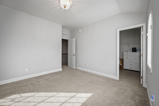 unfurnished bedroom with lofted ceiling, multiple windows, a spacious closet, light colored carpet, and a closet