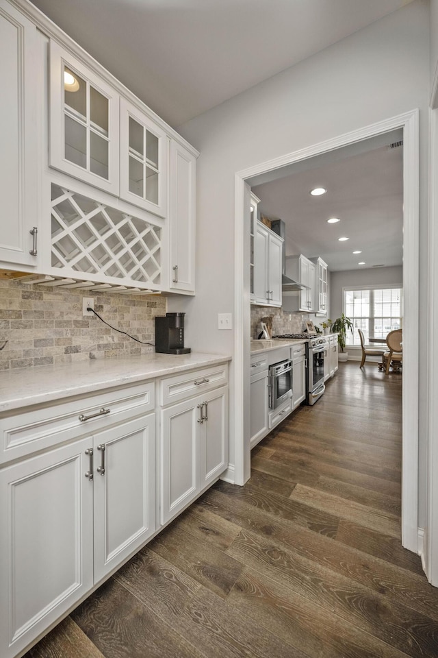 kitchen featuring wall chimney exhaust hood, white cabinetry, dark hardwood / wood-style flooring, wall oven, and backsplash