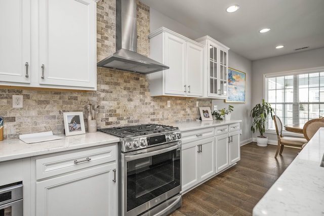 kitchen featuring gas range, white cabinetry, wall chimney exhaust hood, and light stone countertops