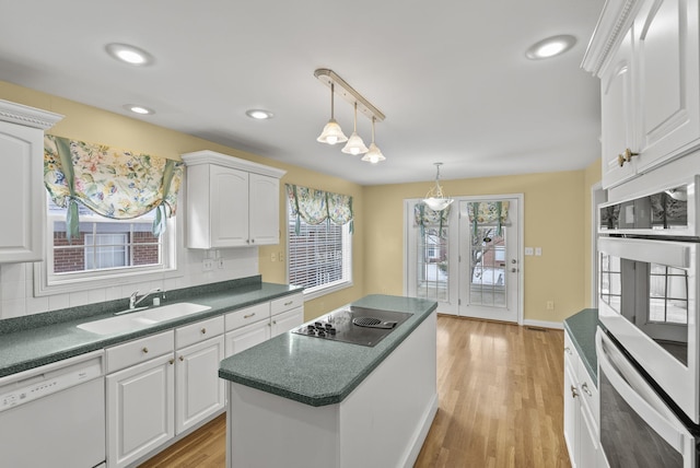 kitchen featuring white cabinetry, sink, white appliances, and decorative light fixtures