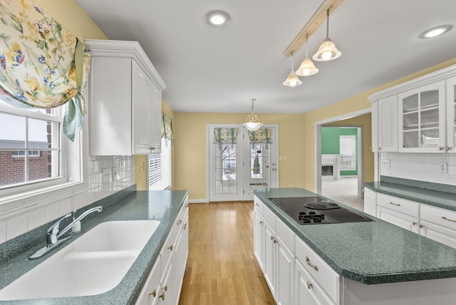 kitchen with sink, a center island, hanging light fixtures, black electric cooktop, and white cabinets