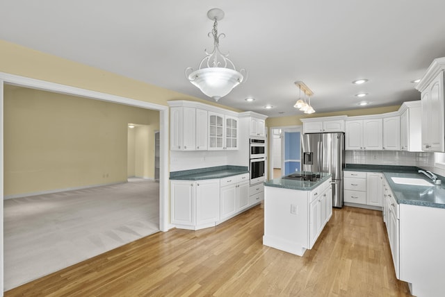 kitchen featuring sink, decorative light fixtures, a kitchen island, stainless steel appliances, and white cabinets