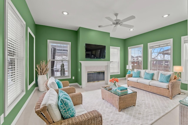 living room featuring ceiling fan, a wealth of natural light, and a fireplace