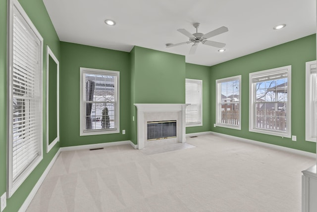 unfurnished living room featuring a fireplace, light colored carpet, and ceiling fan