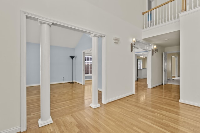 spare room with hardwood / wood-style floors, a high ceiling, and ornate columns