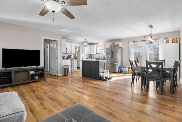 living room with ceiling fan, light hardwood / wood-style floors, and french doors