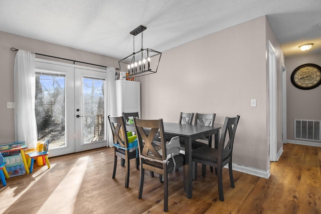 dining room with light hardwood / wood-style flooring, a textured ceiling, and french doors