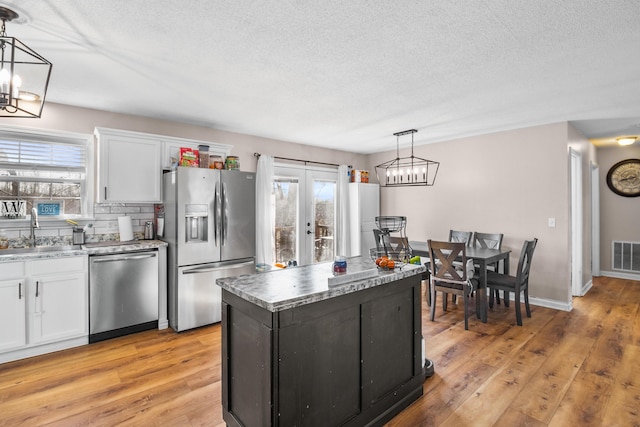 kitchen featuring pendant lighting, sink, white cabinets, and appliances with stainless steel finishes