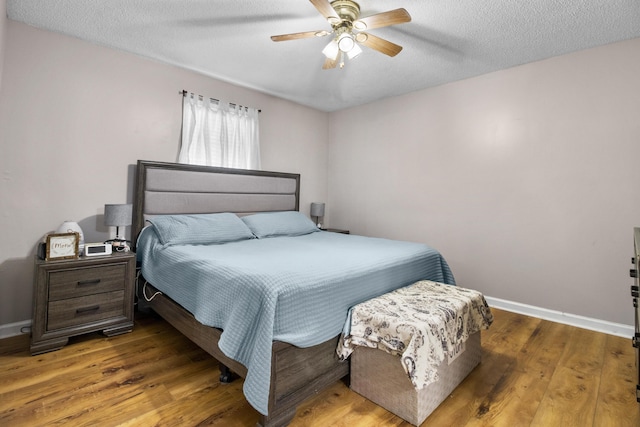 bedroom featuring ceiling fan, dark hardwood / wood-style floors, and a textured ceiling