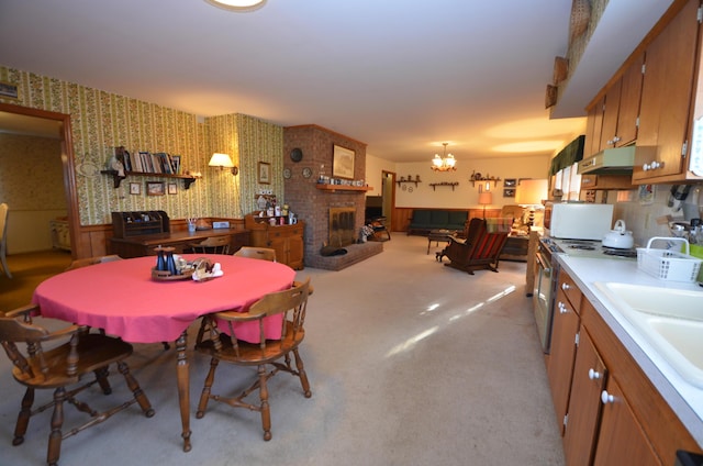 carpeted dining space featuring a brick fireplace, sink, and a chandelier