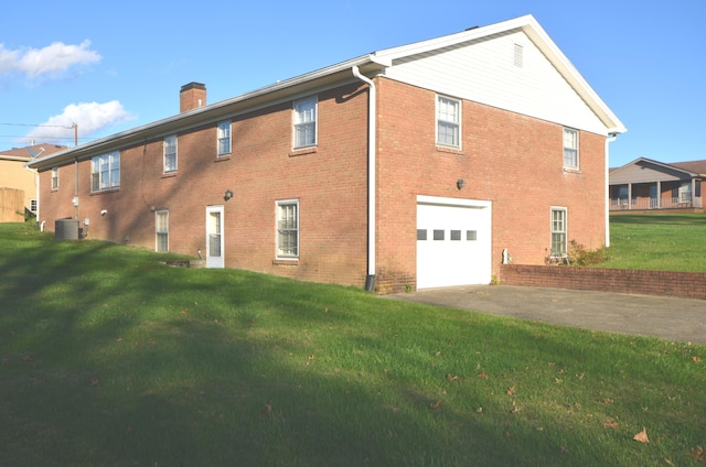 rear view of house featuring a garage, a yard, and central AC