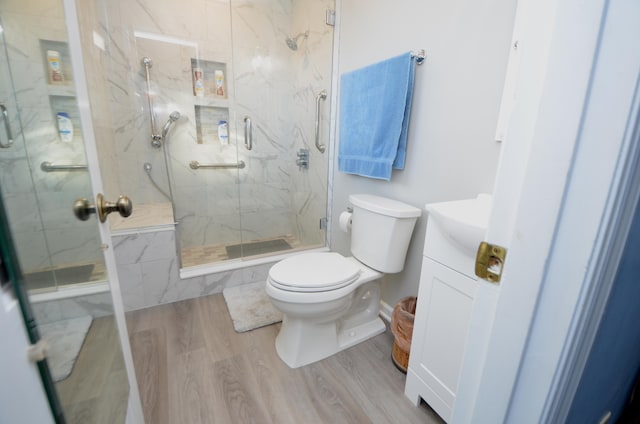 bathroom with vanity, hardwood / wood-style floors, a shower with shower door, and toilet