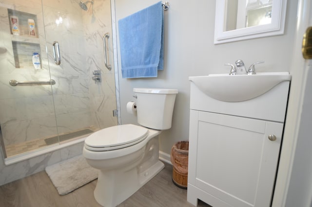 bathroom featuring hardwood / wood-style flooring, vanity, a shower with shower door, and toilet