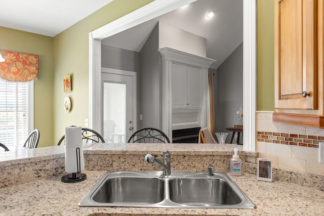 kitchen featuring sink, backsplash, and light stone counters