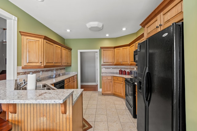 kitchen with sink, black appliances, kitchen peninsula, and a breakfast bar