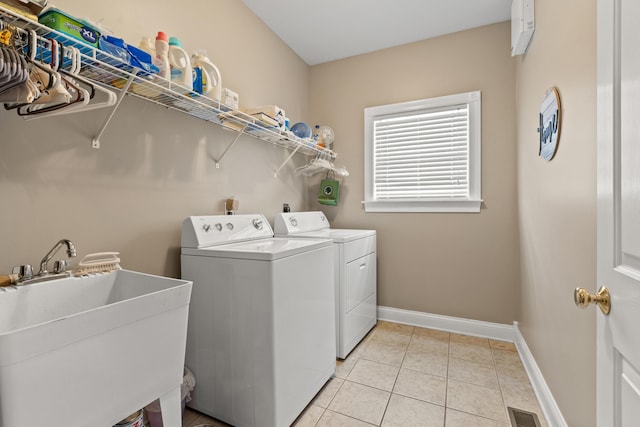 laundry area featuring light tile patterned flooring, separate washer and dryer, and sink