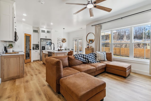 living room with french doors, a healthy amount of sunlight, ceiling fan, and light hardwood / wood-style flooring