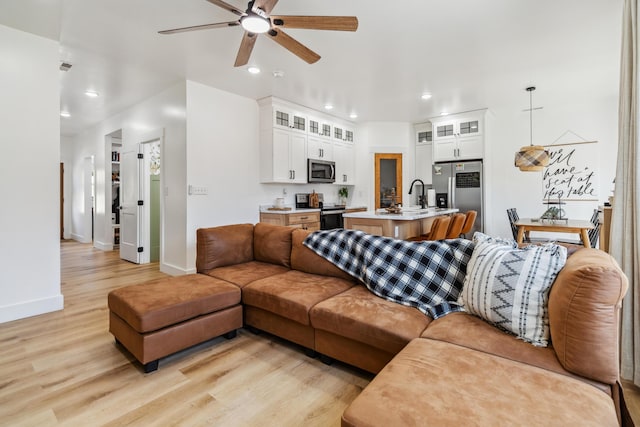 living room featuring sink, light hardwood / wood-style floors, and ceiling fan