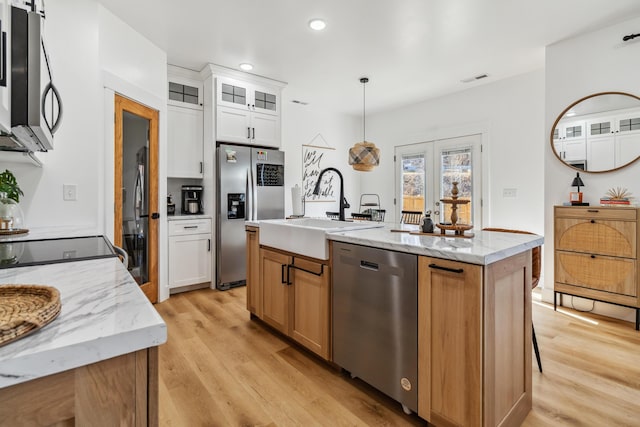 kitchen featuring appliances with stainless steel finishes, sink, white cabinets, hanging light fixtures, and a center island with sink