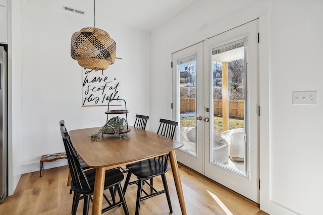 dining room featuring a wealth of natural light, light hardwood / wood-style flooring, and french doors