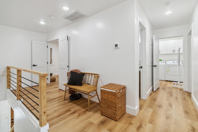 corridor with light hardwood / wood-style flooring and washer and dryer