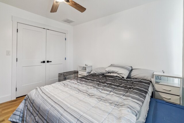 bedroom with light hardwood / wood-style flooring, ceiling fan, and a closet