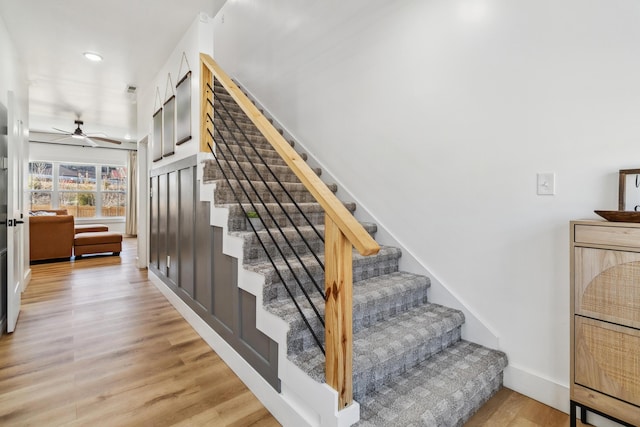 staircase featuring ceiling fan and hardwood / wood-style floors