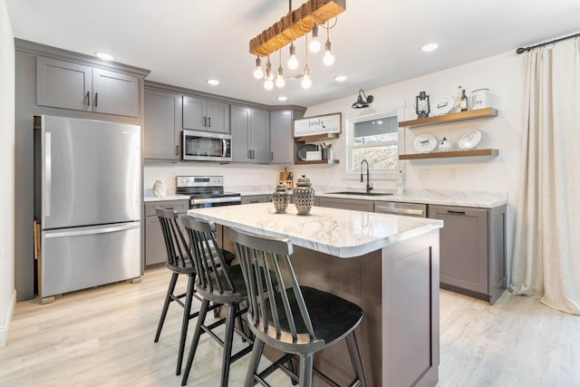 kitchen with a breakfast bar, sink, a center island, hanging light fixtures, and appliances with stainless steel finishes